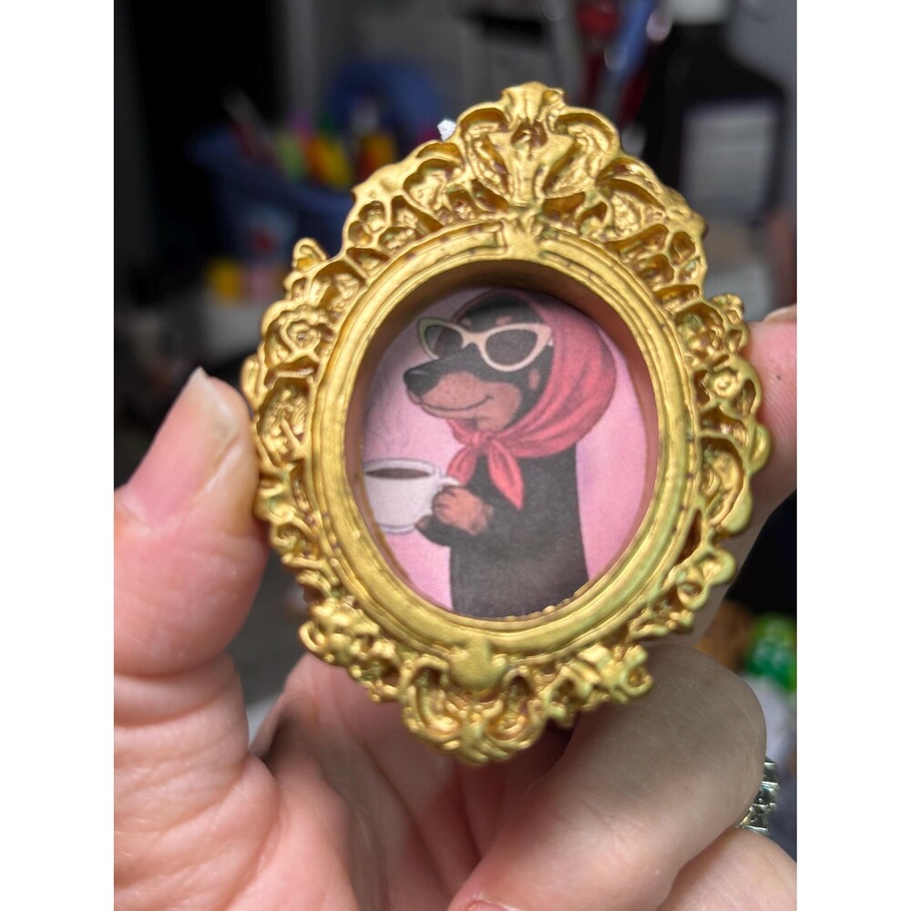 Sassy Dachshund wearing scarf, glasses, and enjoying her coffee, in a gold frame